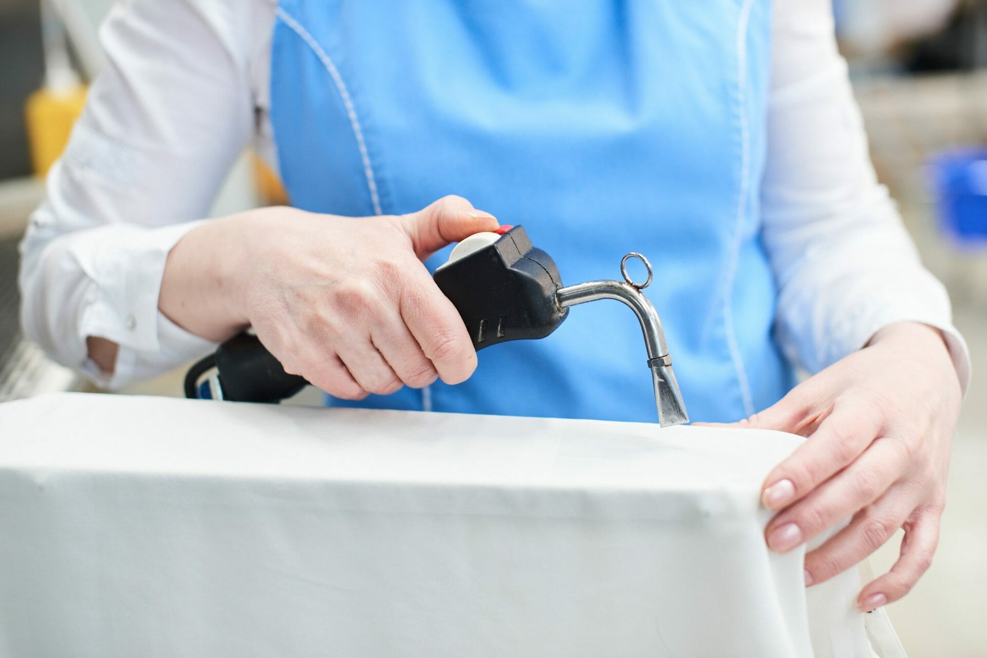 A woman is sewing a pair of jeans on a sewing machine.